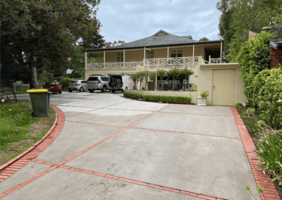 cleaning outdoor pavers in driveway, with red bricks outlining